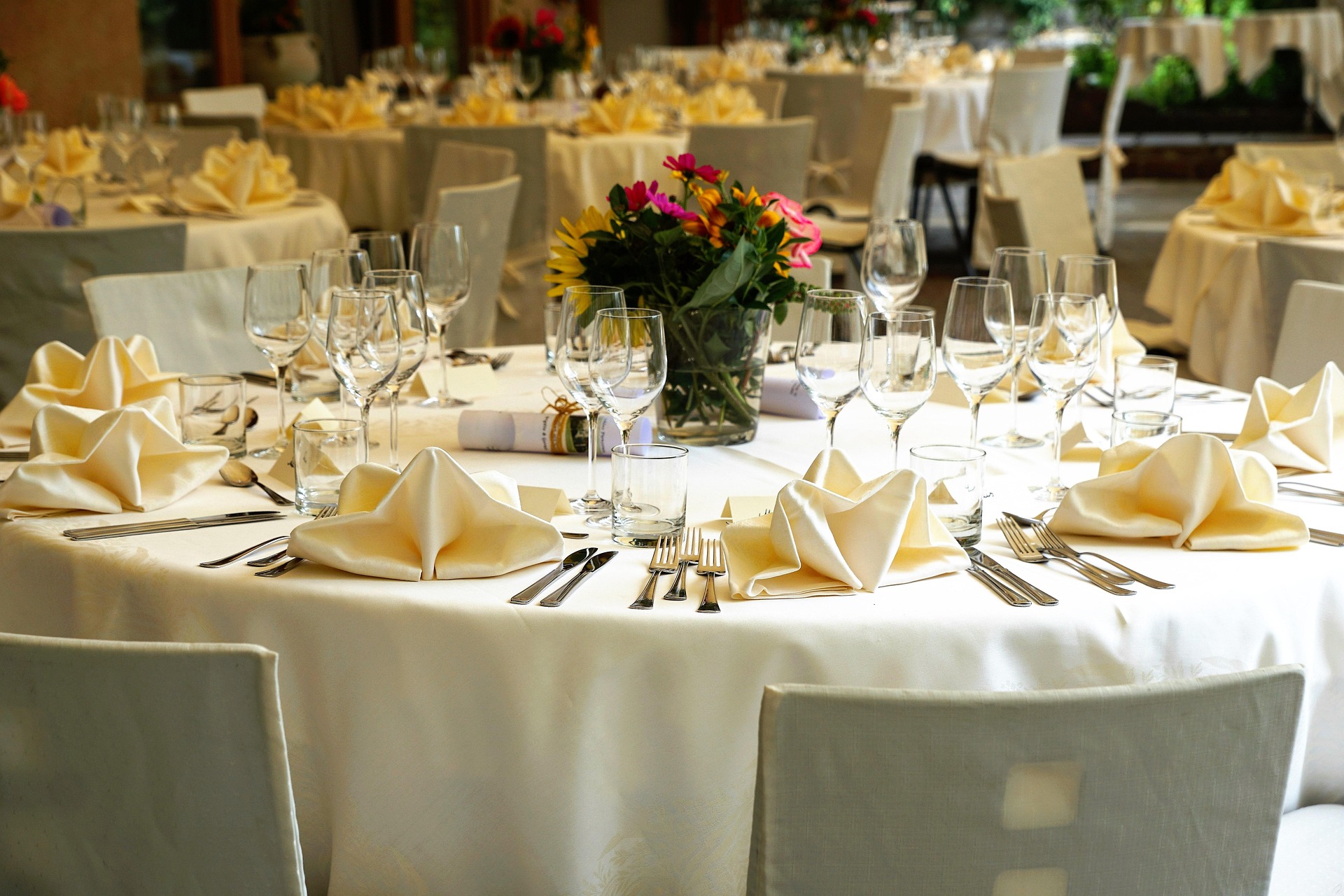 Round banquet tables with folded napkins and glassware at an elegant wedding reception seating plan