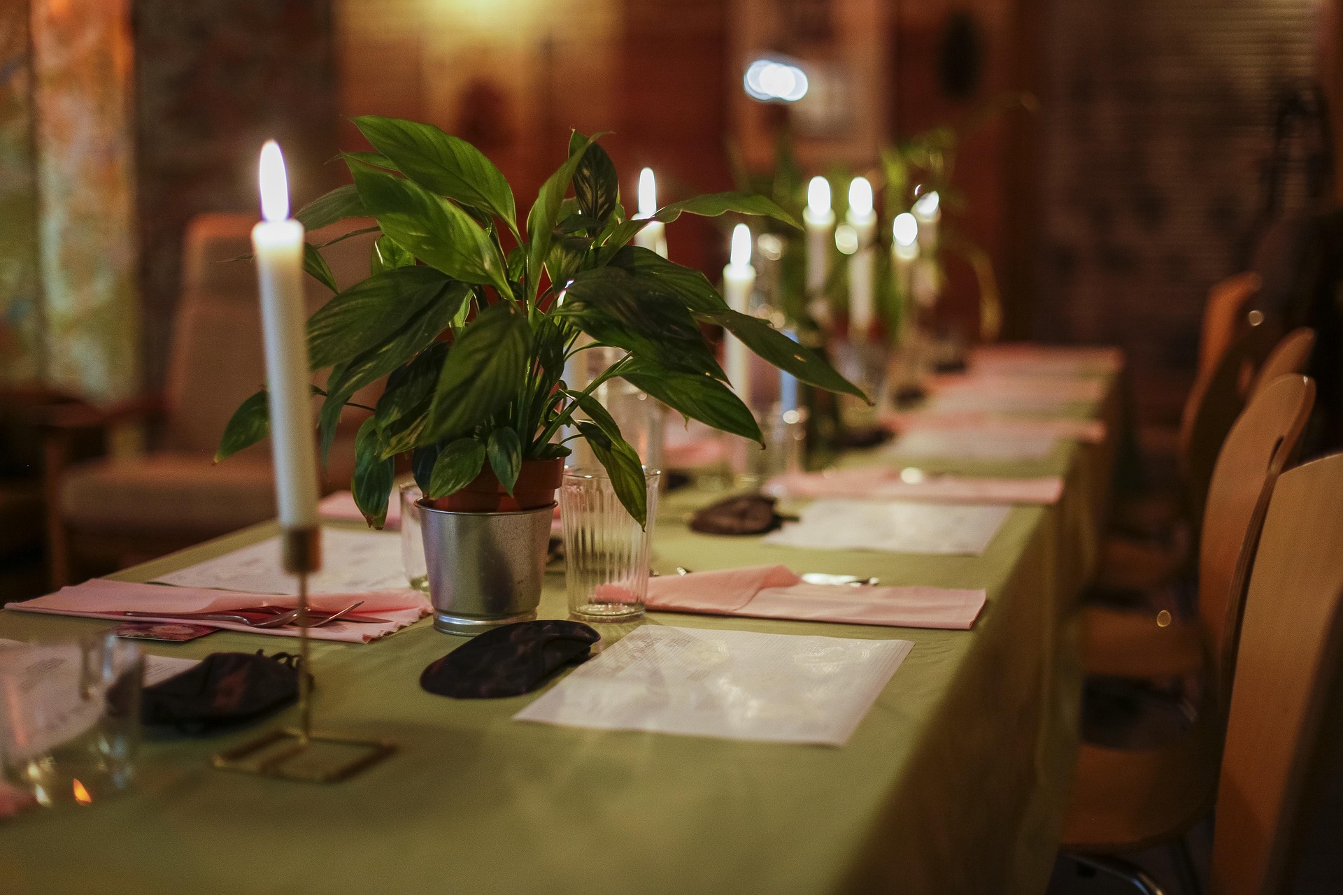 Long candlelit dinner party table with place settings for guests