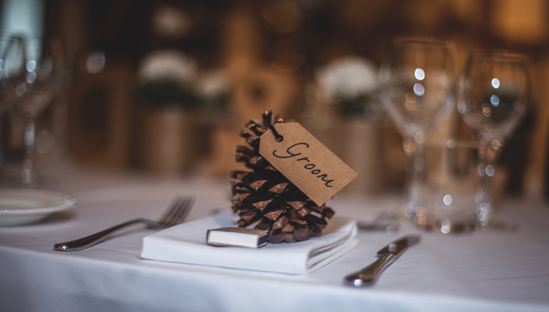 Wedding place card labelled Groom on a napkin at a reception table