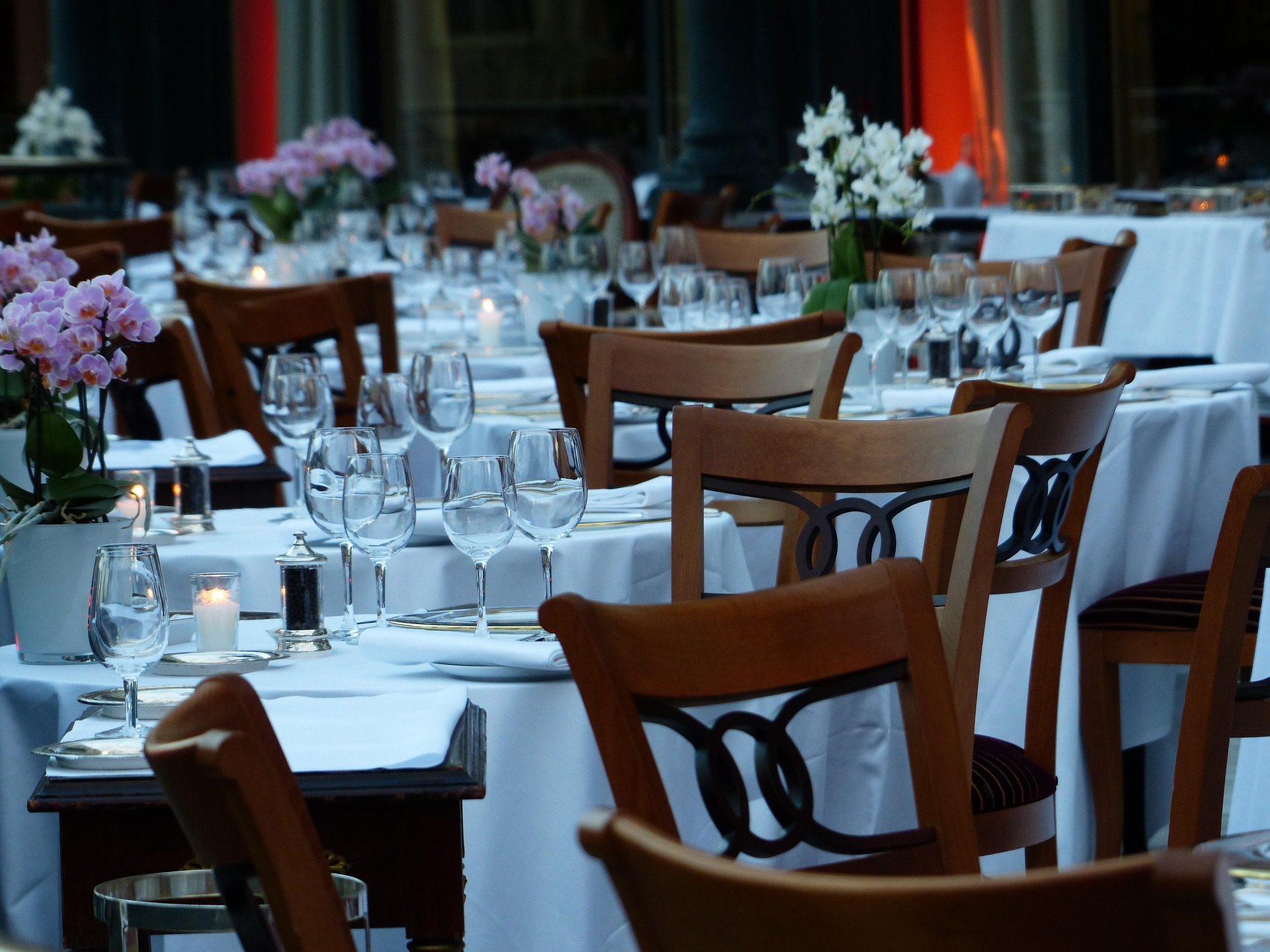 Formal gala dinner tables with white linen, orchids and candlelight arranged by table seating software